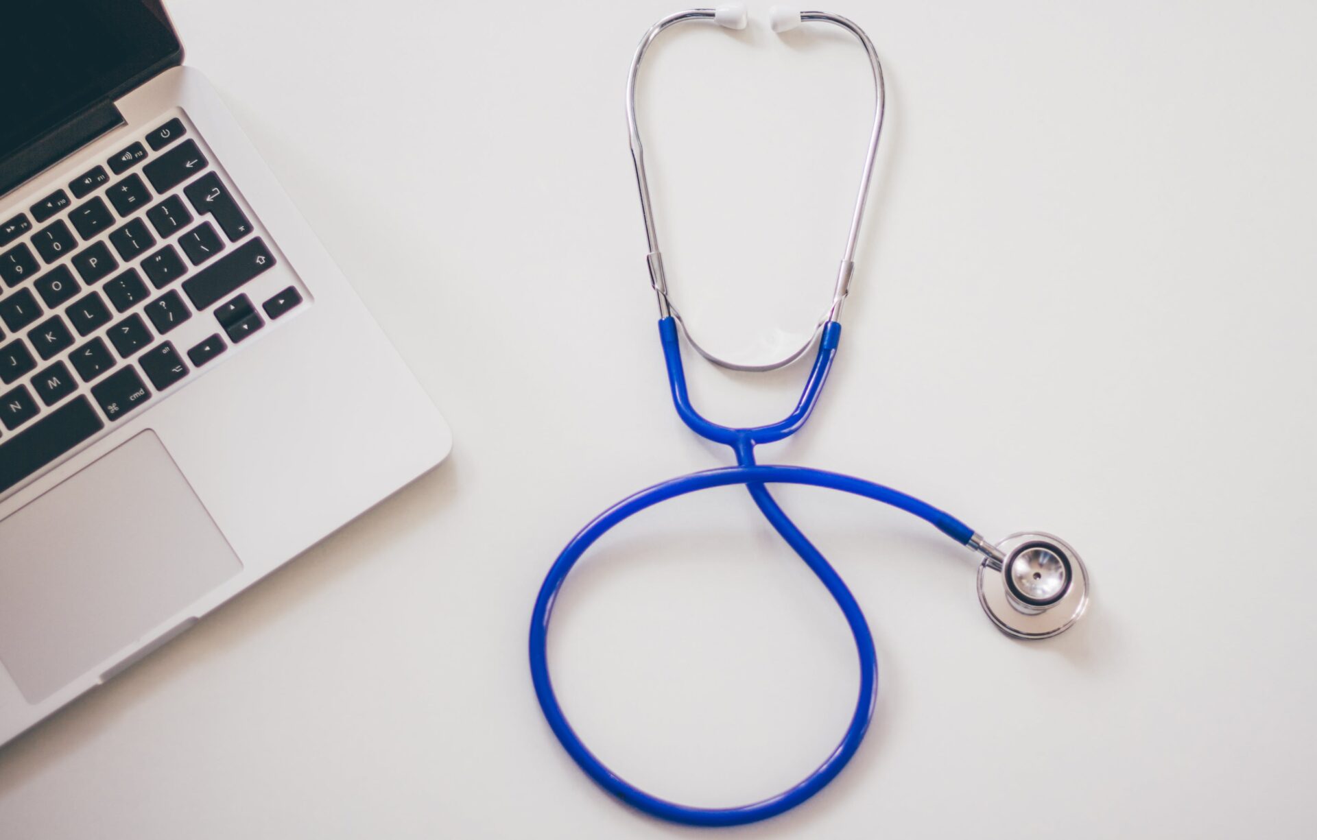 A stethoscope is present beside a laptop on the table.